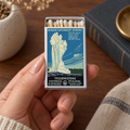 A hand holds a vintage-style Yellowstone National Park matchbox with matches visible inside. The box features a blue and cream illustration of a geyser eruption, with text reading 'Yellowstone National Park' and 'Ranger Naturalist Service.